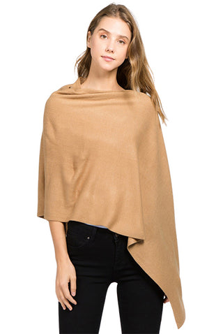 A model in a camel-colored fabric poncho and black slacks.