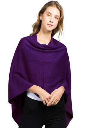 A woman in an eggplant-colored fabric poncho and black pants.