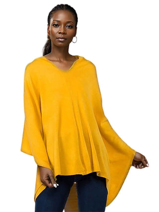 A woman wearing a mustard yellow poncho and dark blue pants.