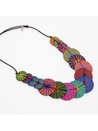 Angled view of A necklace of Round multicolored wooden beads that are layered together and complemented by multiple thread colors that wraps around each bead, on an adjustable cord.