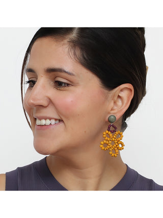 Earrings in wine and mustard colored loops of beads, on a smiling model.