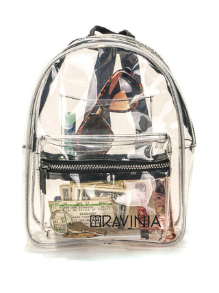 Straight-on view of a clear backpack with the Ravinia name and logo in its lower portion, and money, sunglasses, lip balm and a cassette tape visible inside.