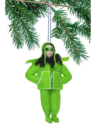 A felt ornament hanging on a tree branch, depicting Billie Eilish in a green outfit and black hair.