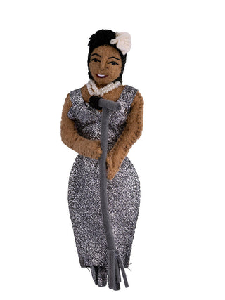 A felt ornament depicting jazz singer Billie Holiday at a microphone, wearing a silver spangled dress and pearls.