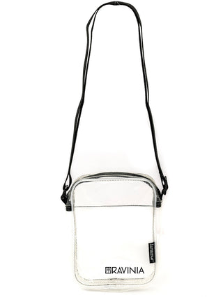 A transparent brick bag with the Ravinia logo and name in black, and a black shoulder strap that is extended above the bag..