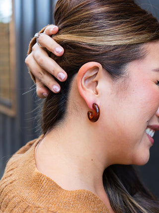 A model wearing the brown hoops with a pumpkin colored sweater.