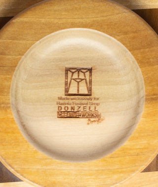 Bottom of a wooden bowl with the Ravinia logo, a message about exclusivity, and Donzell Creative Works at the bottom.