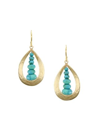 A pair of earrings with a brass cutout teardrop with a tiered stack of turquoise beads in the center. 
