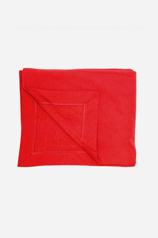 A red blanket with the lower left corner folded back, revealing the seams and construction of the blanket.