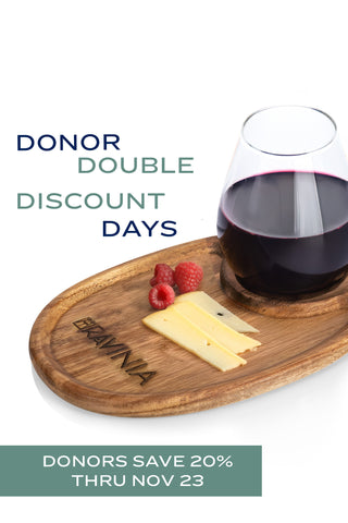 A wooden plate with the Ravinia logo on it, holding a wine glass, cheese and raspberries, with the text DONOR DOUBLE DISCOUNT DAYS and DONORS SAVE 20% THRU NOV 23.