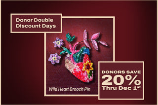 A colorful embroidered brooch in the shape of a heart with flowers growing out of it on a maroon background, with the words Donor Double Discount Days: Donors Save 20% Thru Dec 1st.
