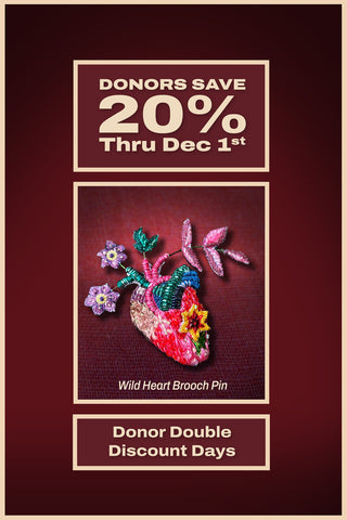 A colorful embroidered brooch in the shape of a heart with flowers growing out of it on a maroon background, with the words Donor Double Discount Days: Donors Save 20% Thru Dec 1st.