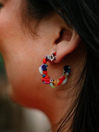 A closeup of someone wearing the Flora Hoops in Fiesta.