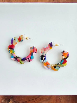 A pair of colorful acrylic hoop earrings with a floral shape.