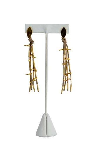 The earrings, made of a gold-plated leaf-shaped piece with four gold colored cords hanging from it, holding bronze gold-plated ingots.