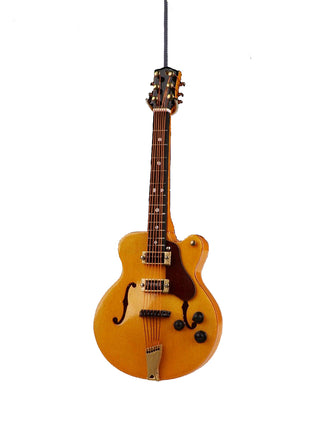 An ornament in the shape of a hollow body electric guitar, hanging on a gray string.