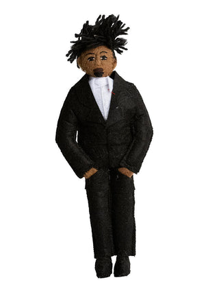 A felt ornament representing hip hop artist Jay Z, in black jacket and pants with a white shirt.