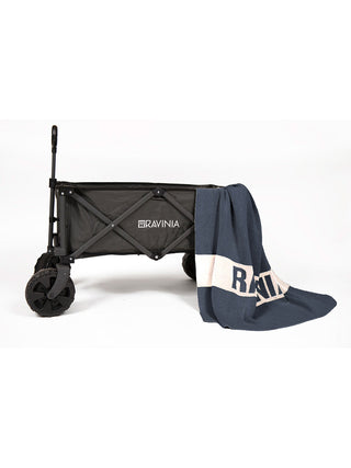 A black wagon with the Ravinia logo and a denim and cream knit blanket draped over it that says Ravinia.