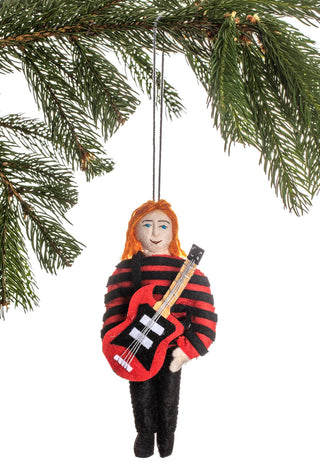 A felt ornament depicting Nirvana's Kurt Cobain in a striped shirt, with a red guitar, hanging from the branch of a holiday tree.