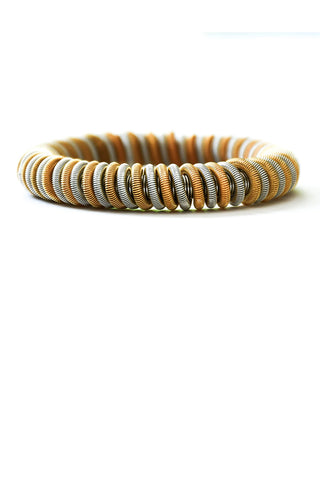 A bracelet made from coils of gold and silver colored wire.