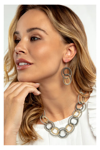 A woman in profile wearing earrings of multiple loops in gold, silver and gray piano wire.