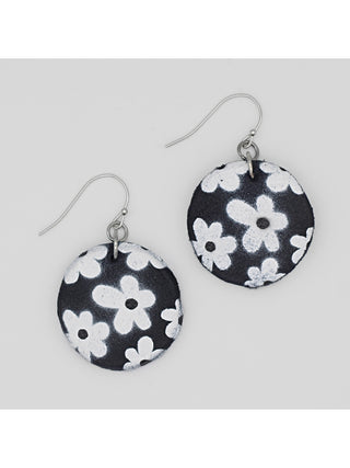 Circular black earrings with a white flower print, with a French wire above.