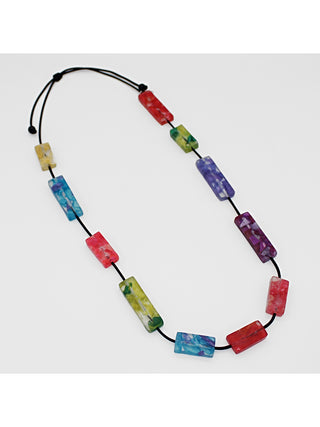 Angled view of a A necklace with rectangular resin beads in rainbow colors from red to blue to green to purple, on a cord.
