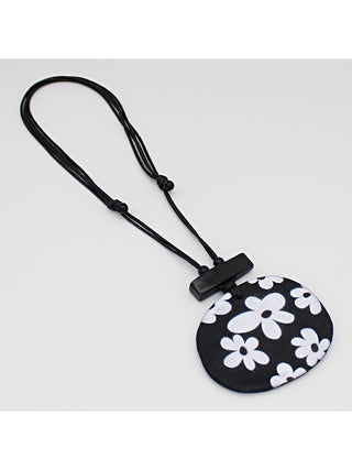 Angled view of A playful flower design in black and white, on a leather cord.