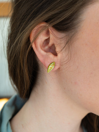 A model wearing the olive green leaf stud earrings.