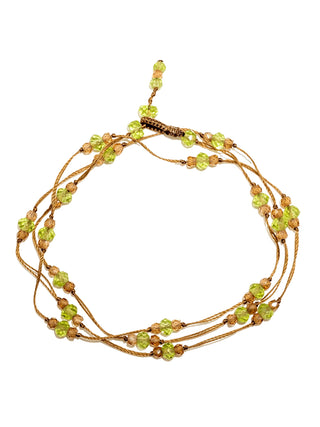 The strand of peridot beads coiled as a bracelet or anklet.