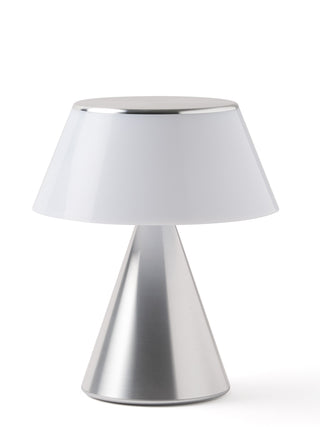 A lamp with a triangular aluminum base and an unilluminated shade.