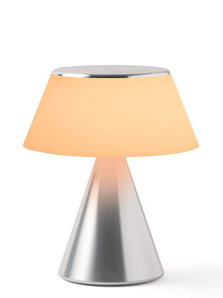 A lamp with a triangular aluminum base and an illuminated gold shade.