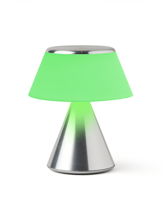 A lamp with a triangular aluminum base and an illuminated green shade.