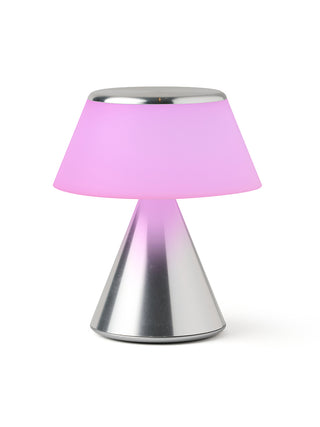 A lamp with a triangular aluminum base and an illuminated  pink shade.