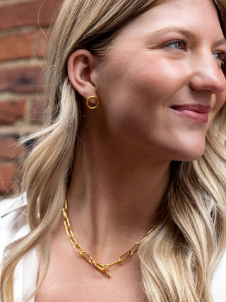 A close-up of a model wearing a gold chain link necklace.