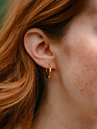 A close-up image of a model wearing the gold Luxe Selena Hoops.