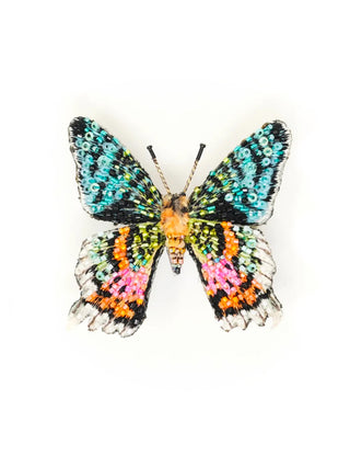 An embroidered brooch in the form of a teal, orange, and pink Madagascar sunset moth.