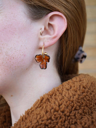 A close-up of a model wearing the amber magnolia hoops.