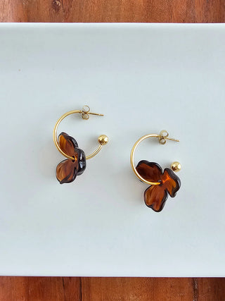 A pair of gold hoop earrings with an amber resin flower on each.