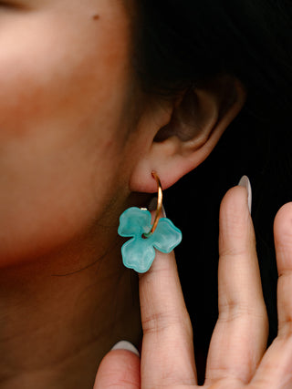 A close-up of a model wearing the aqua magnolia hoops.