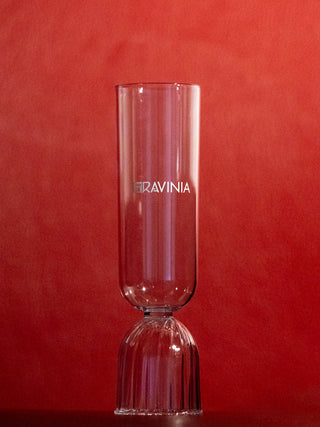 The clear Milan champagne glass with the Ravinia name and logo in white displayed on a red background.