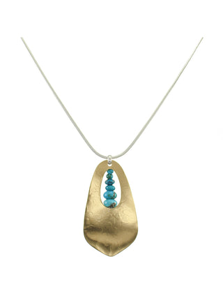 A hammered brass cutout teardrop pendant with a graduated turquoise bead stack in the center, hanging from a silver snake chain. 