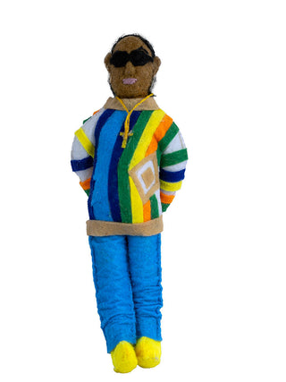 A felt ornament of the Notorious B.I.G. wearing a colorful striped shirt, blue pants, and a cross necklace.