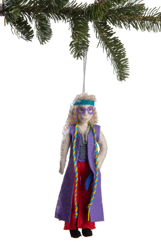A felt ornament of Janis Joplin in a purple and red outfit, complete with headbanding, hanging from a holiday tree branch.