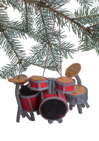 An ornament of a red felted drum set hanging from the branch of a Christmas tree.