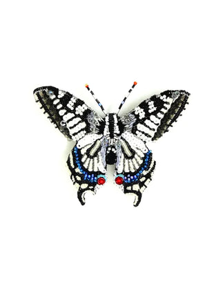 An embroidered brooch in the form of a black, white, and blue old world swallowtail butterfly.