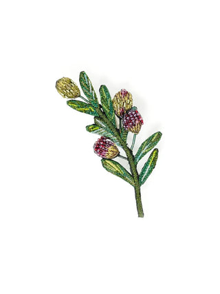 An embroidered brooch in the shape of a green olive branch.