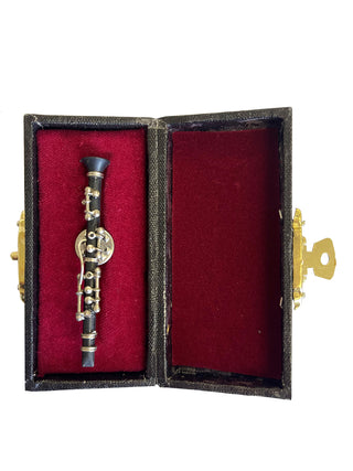 A lapel pin that looks like a black clarinet, in a red, velvet-lined case.