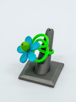 A clip of the turquoise and green flower power ring with the flower spinning.