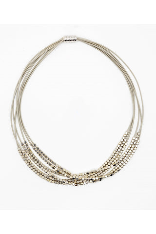 A necklace comprised of Six strands of soft, supple, silver-toned piano wire, each with plentiful beads. Magnetic clasp.